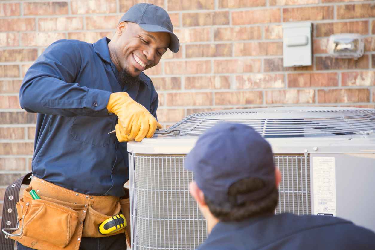 A team of HVAC technicians performing maintenance on an HVAC system.