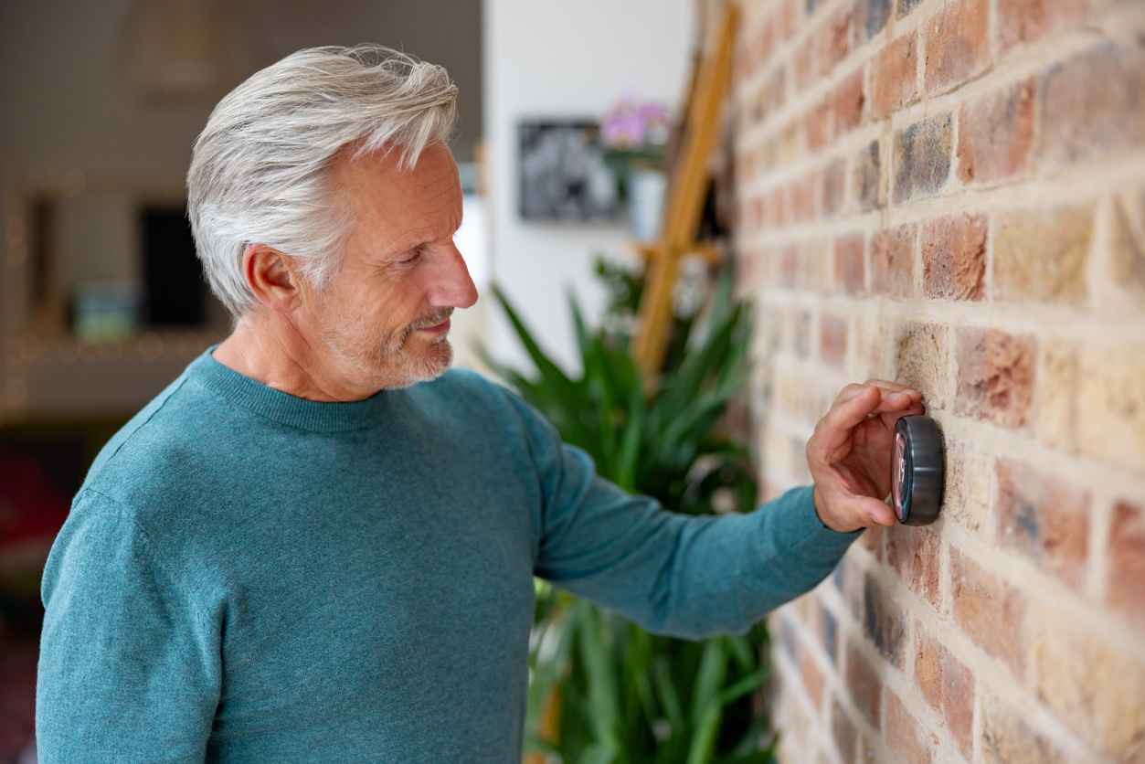 Senior man adjusting the temperature using a smart thermostat